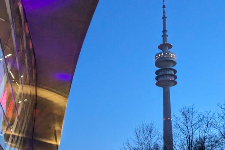 Fernsehturm in München bei Dämmerung, links ein Teil des Olympiastadions.